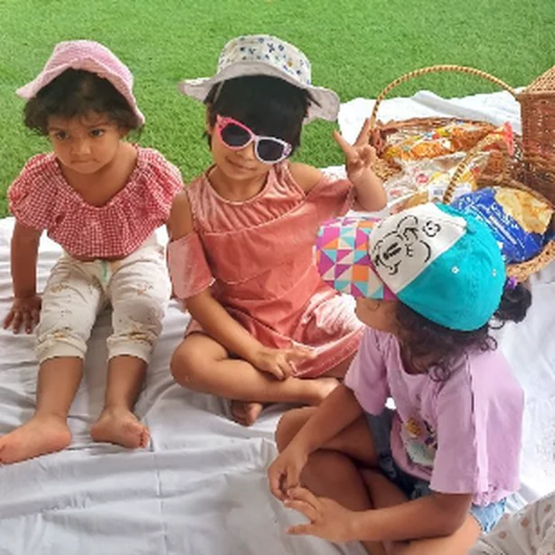 Three children sitting together in sun hats